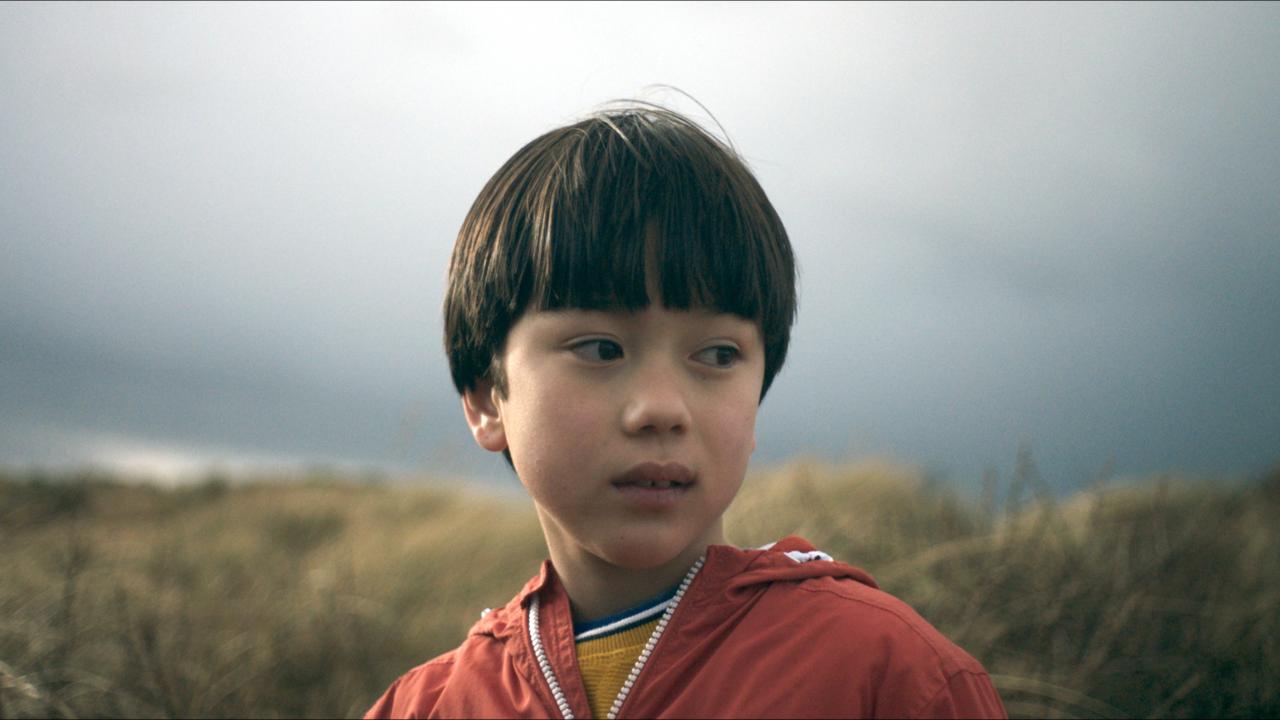 Still aus dem Dokumentarfilm WARUM ICH EUCH NICHT IN DIE AUGEN SCHAUEN KANN: Porträt eine kleinen Jungen, der etwas schüchtern zur Seite blickt.