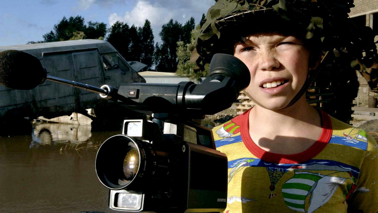 Filmstill aus dem Kinderfilm DER SOHN VON RAMBOW: Ein etwa 11-jähriger Junge, der einen Soldatenhelm trägt, steht vor einer Super8-Kamera.