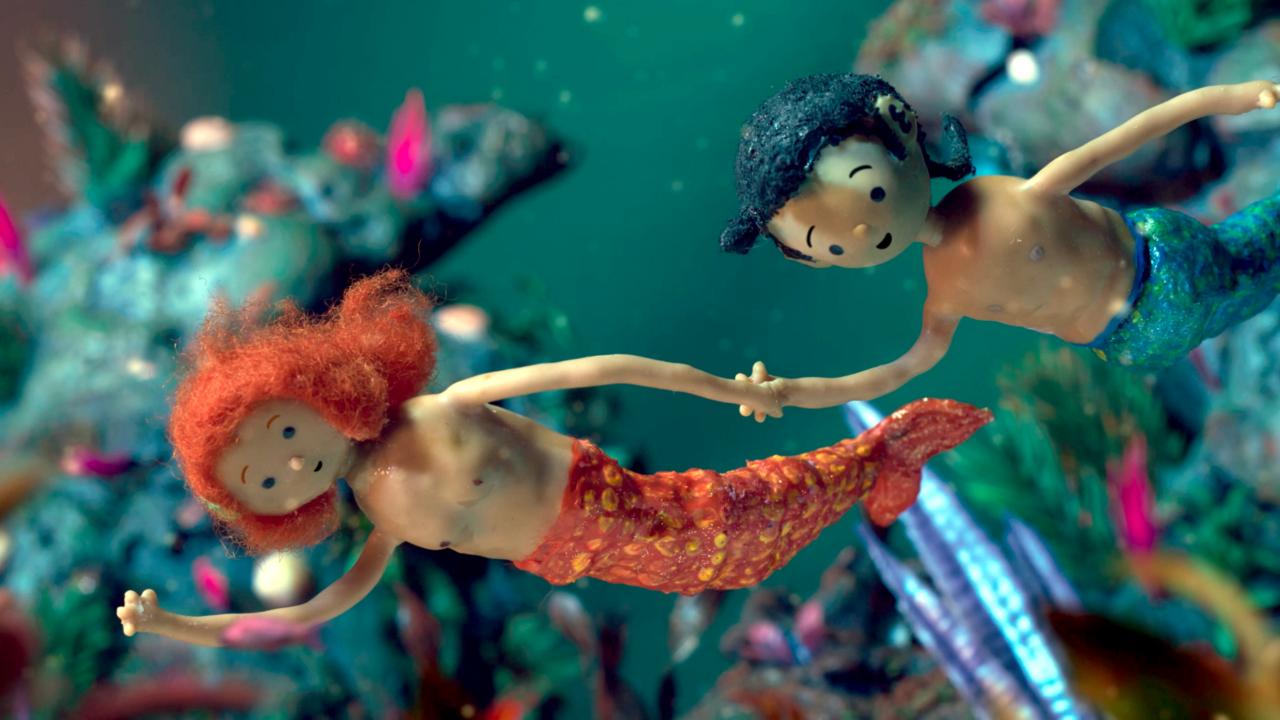 Still aus dem Puppentrickfilm ROQUE, DIE MEERJUNGFRAU: Zwei Nixen schwimmen unter Wasser und halten sich dabei an den Händen.