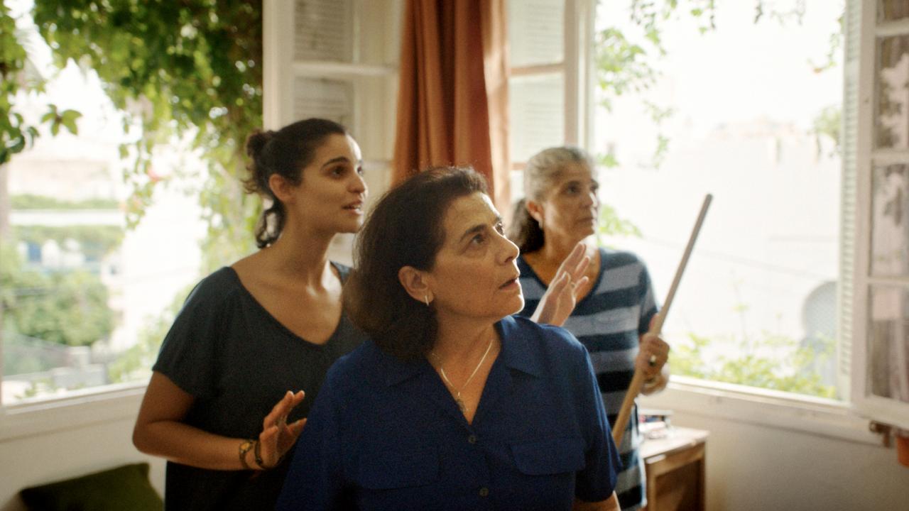 Still aus dem Drama MIT LEISER STIMME: Drei Frauen unterschiedlichen Alters stehen in einem lichtdurchfluteten Zimmer und schauen gespannt in eine Richtung.