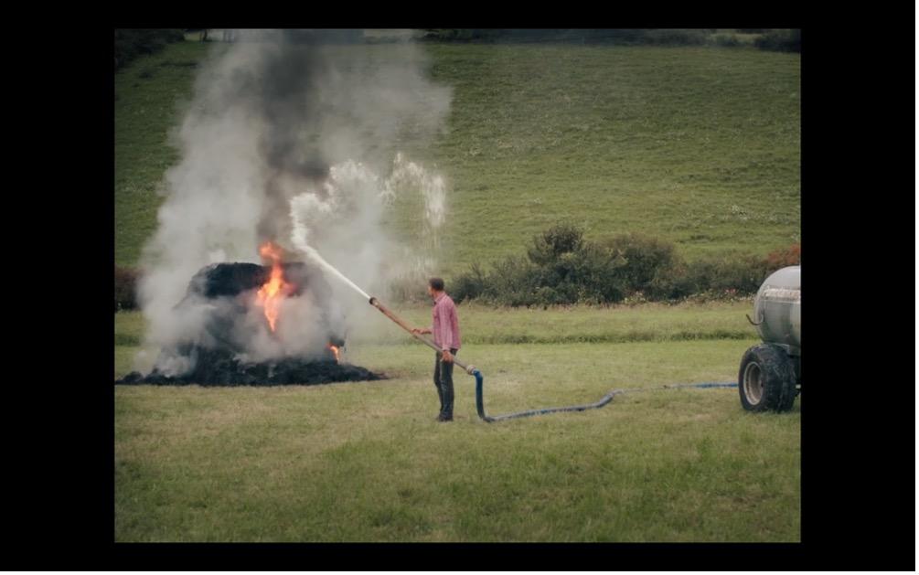 Screenshot aus MILCH INS FEUER: Der Bauer löscht ein Feuer auf einer Wiese mit Milch.