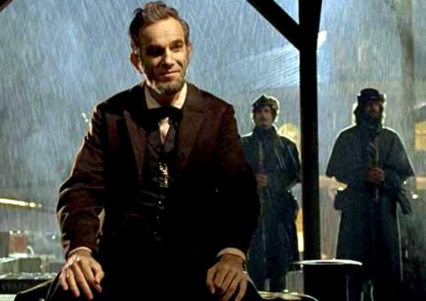Still aus dem Biopic LINCOLN: Die Titelfigur sitzt nachts bei Regen unter einem Dach. Im Hintergrund stehen zwei Soldaten.