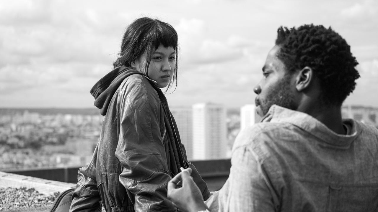 In Schwarz-Weiß: Eine junge Frau und ein junger Mann sitzen auf dem Dach eines Hochhauses.