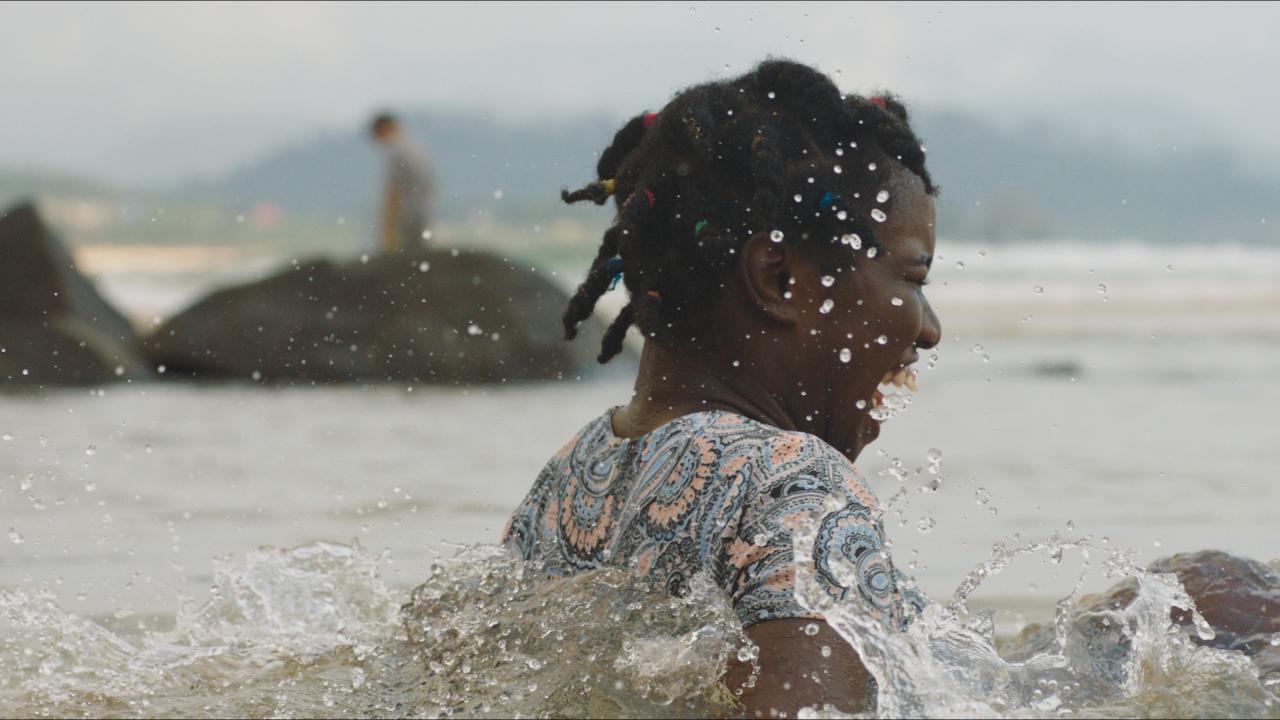 Ein Mädchen im Teenageralter badet lachend im Meer.