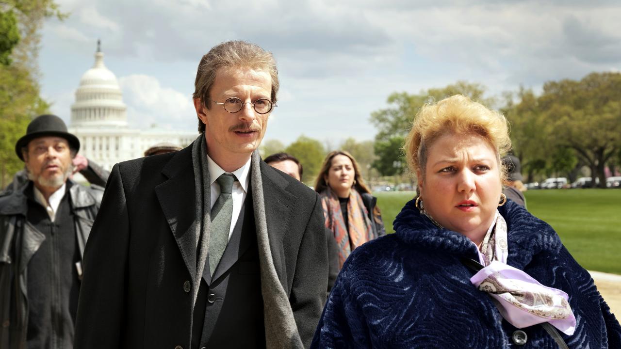 Szenenbild aus dem Drama "Rabiye Kurnaz gegen George W. Bush": Der Anwalt Bernhard Docke, ein großer, schlanker Mann mit Schnauzbart, und seine deutsch-türkische Mandantin Rabiye Kurnaz laufen nebeneinander. Sie nehmen an einem Schweigemarsch in Washington D.C. teil. Im Hintergrund ist die weiße Kuppel des Capitols erkennbar.