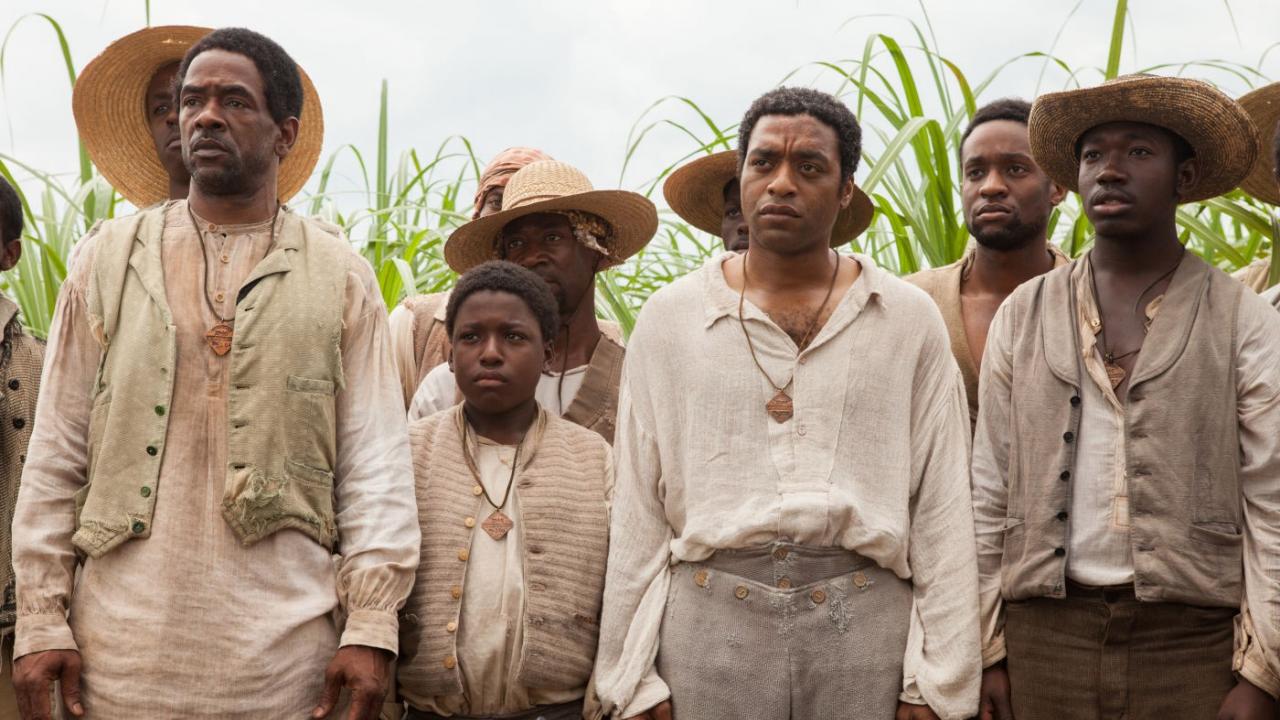 12 Years a Slave, Szenenbild: ein Gruppe von Menschen in altmodischer Kleidung stehen vor einem Feld und gucken ernst.