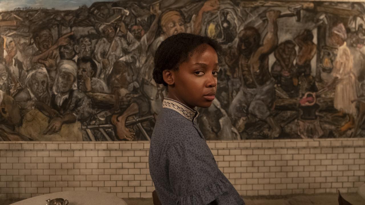 Underground Railroad, Szenenbild: Eine junge Frau steht vor einem Wandgemälde und schaut in die Kamera