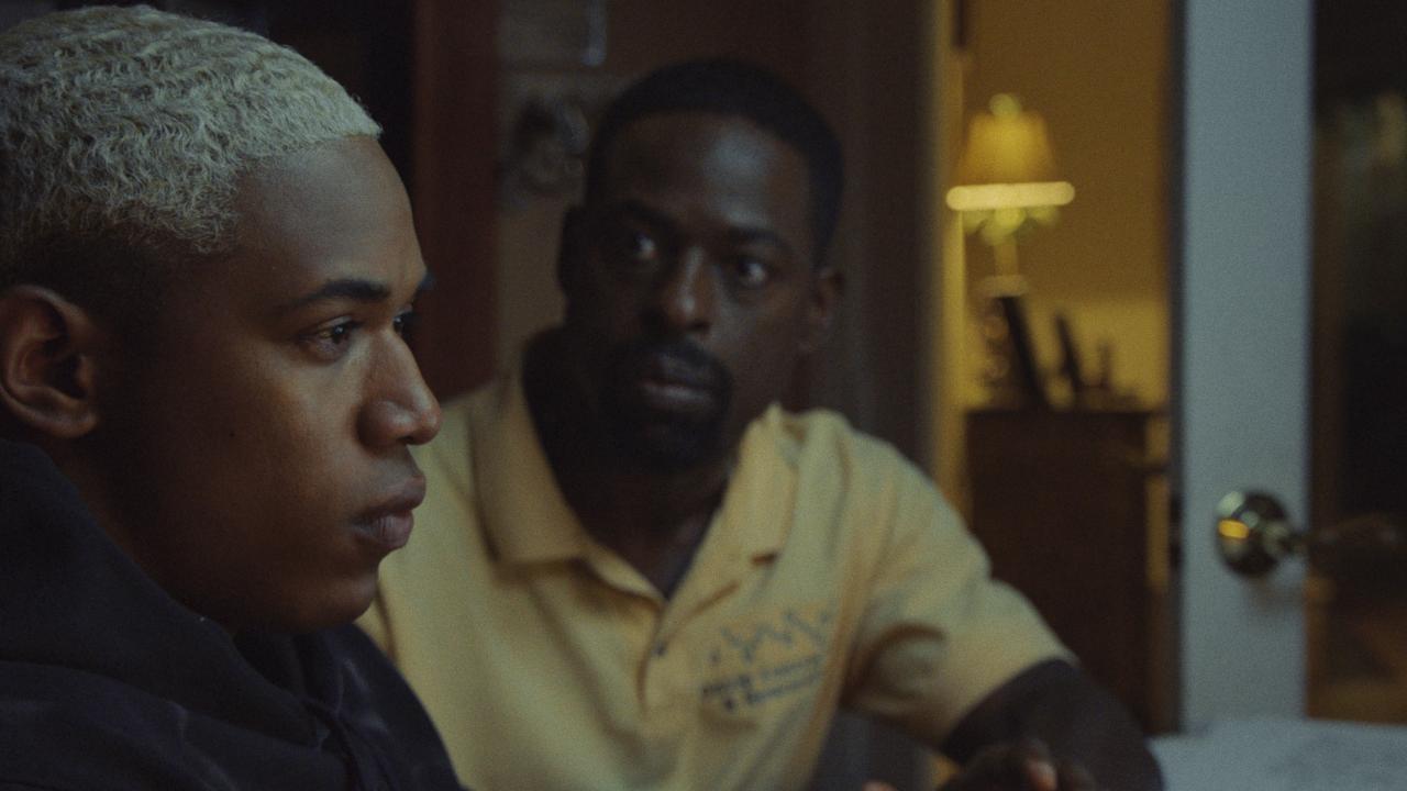 Waves, Szenenbild: Nahaufnahme eines afroamerikanischen Teenagers mit blondierten Haaren. Hinter ihm sitzt ein älterer, afroamerikanischer Mann, der ihn ernst anschaut.