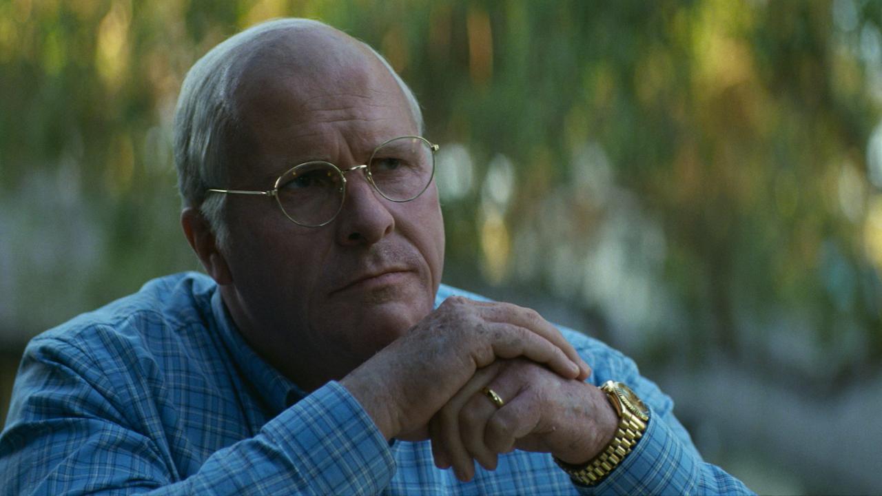 Vice – Der zweite Mann, Szenenbild: Nahaufnahme eines grauhaarigen Mannes mit Brille und im blauen Hemd. Er hat die Arme aufgestützt und hält die Hände übereinander geschlagen. 