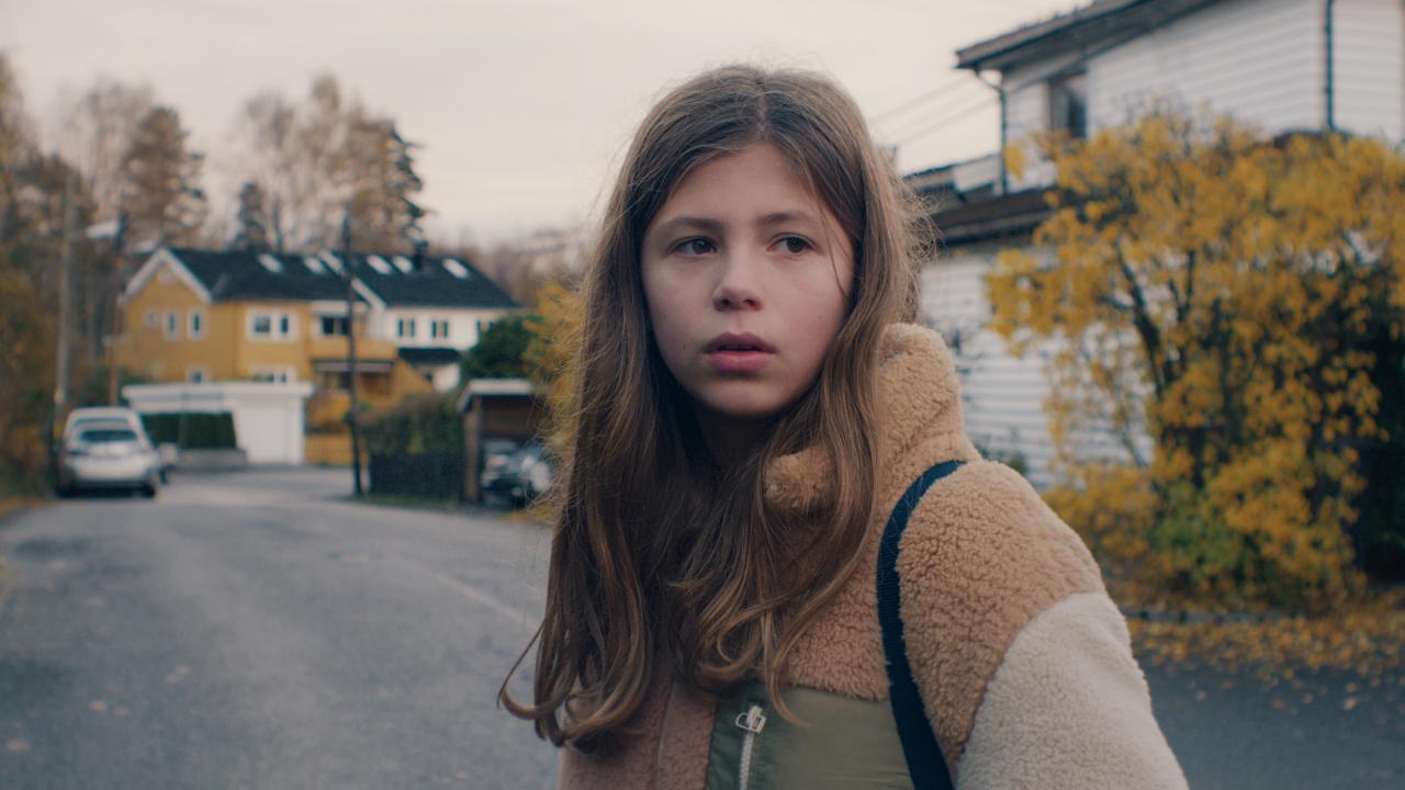 Still aus dem Film LARS IST LOL: Ein Mädchen steht in einer Wohnstrasse und schaut nachdenklich.