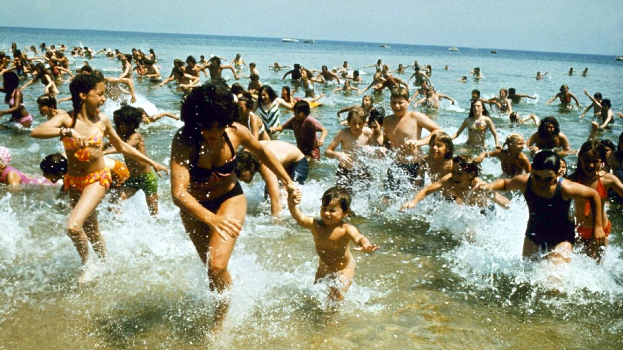 Filmstill aus dem Film DER WEISSE HAI: Eine Menschenmasse stürmt in Panik aus dem Meer an den Strand.
