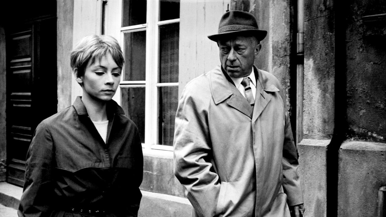 Filmstill aus KARLA: Eine junge Frau mit kurzen Haaren geht neben einem Mann mit Mantel und hut, der sie skeptisch anschaut.