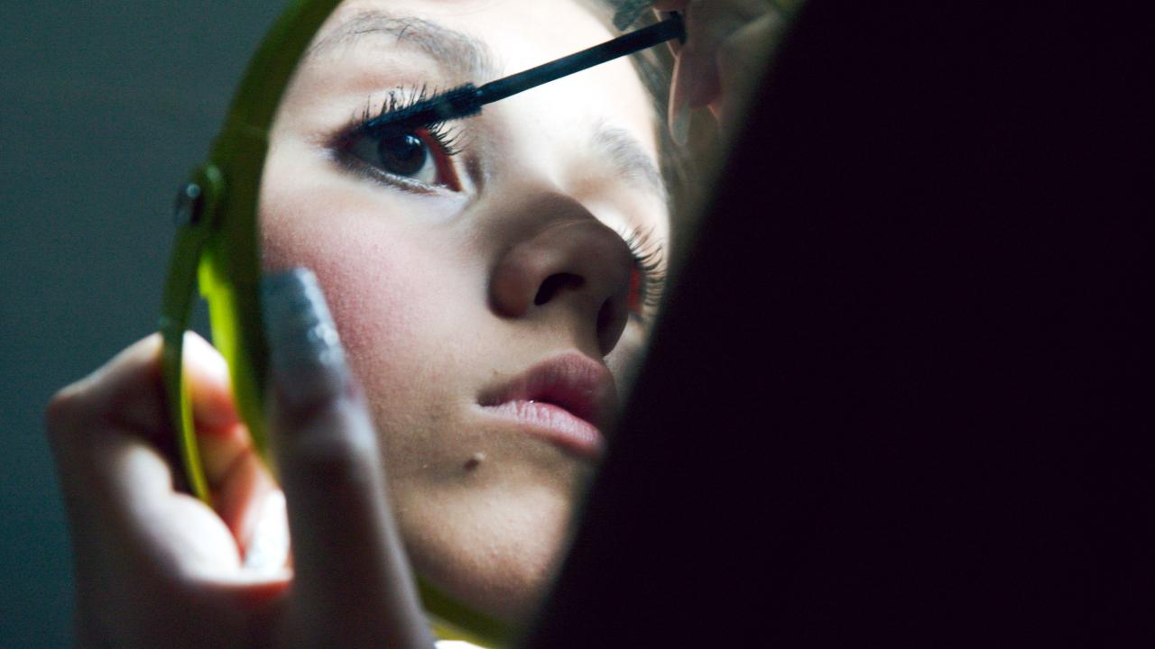 Still aus dem Dokumentarfilm GIRLS DON'T CRY: Nahaufnahme eines Mädchen, das sich schminkt. Man sieht ihr Gesicht nur im Handspiegel.
