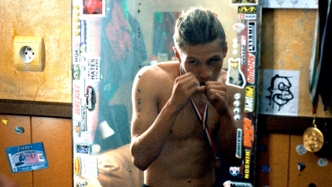 Still aus dem Drama WILD FOXES: Ein jugendlicher steht mit erhobenen Fäusten und mit nacktem Oberkörper vor einem Spiegel. Er trägt eine Medaille am Hals.