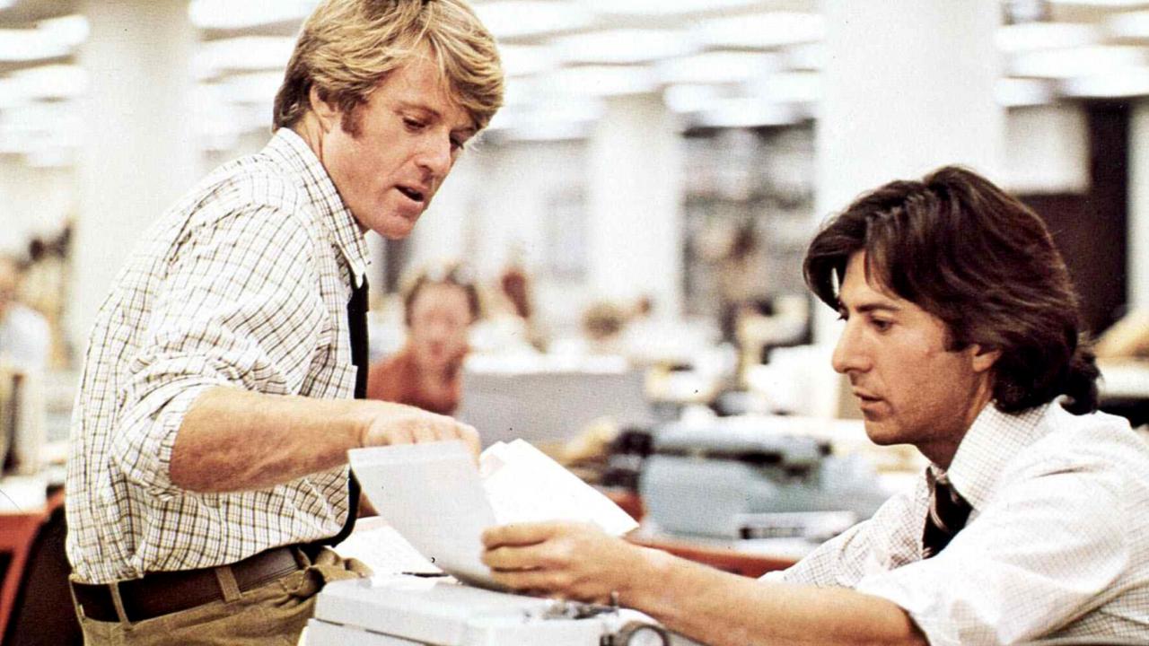 Still aus dem Drama DIE UNBESTECHLICHEN: Roberr Redford und Dustin Hoffman in der Rolle der Washington-Post-Journalisten Bob Woodward und Carl Bernstein. Die beiden sitzen in einem Großraumbüro und sprechen miteinander.  