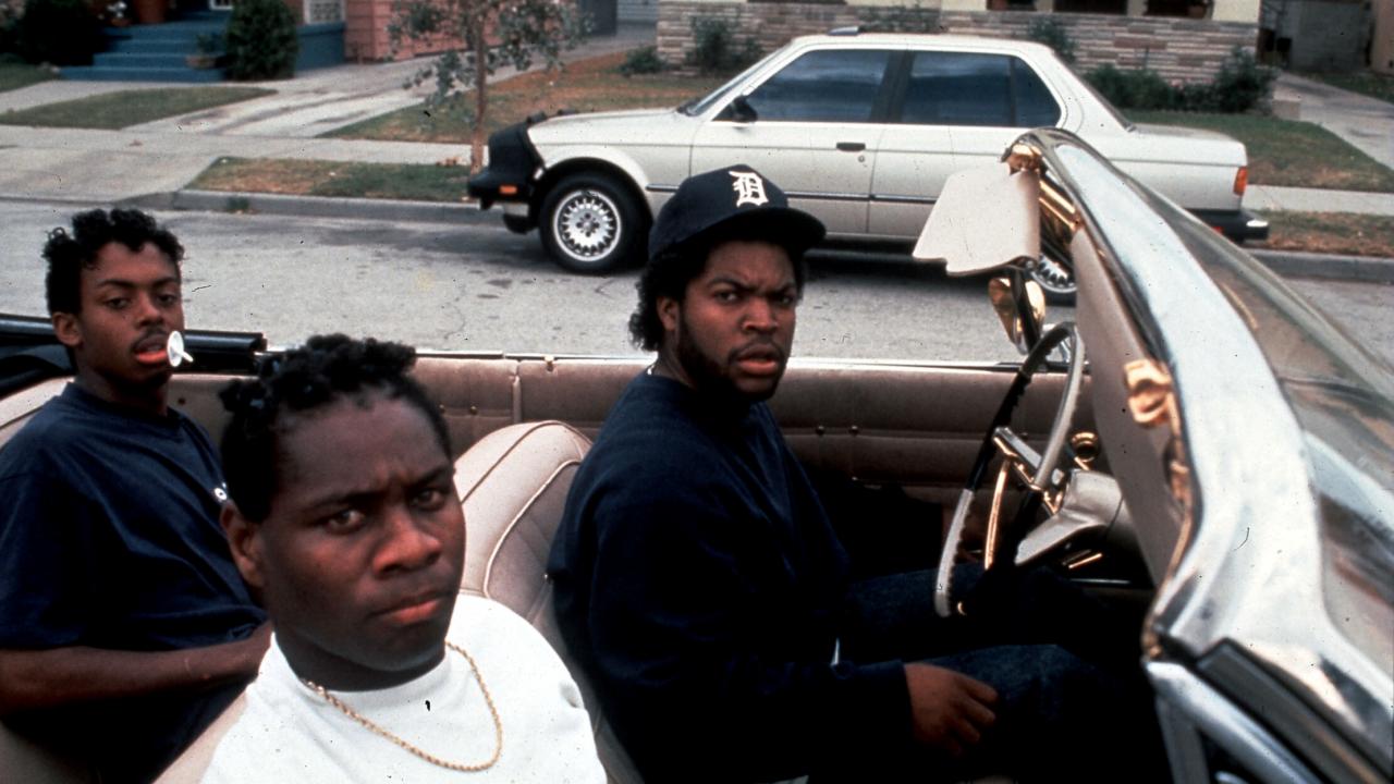 Still aus dem Drama BOYZ N THE HOOD: Drei junge Schwarze sitzen in einem Cabriolet und schauen ernst in die Kamera.