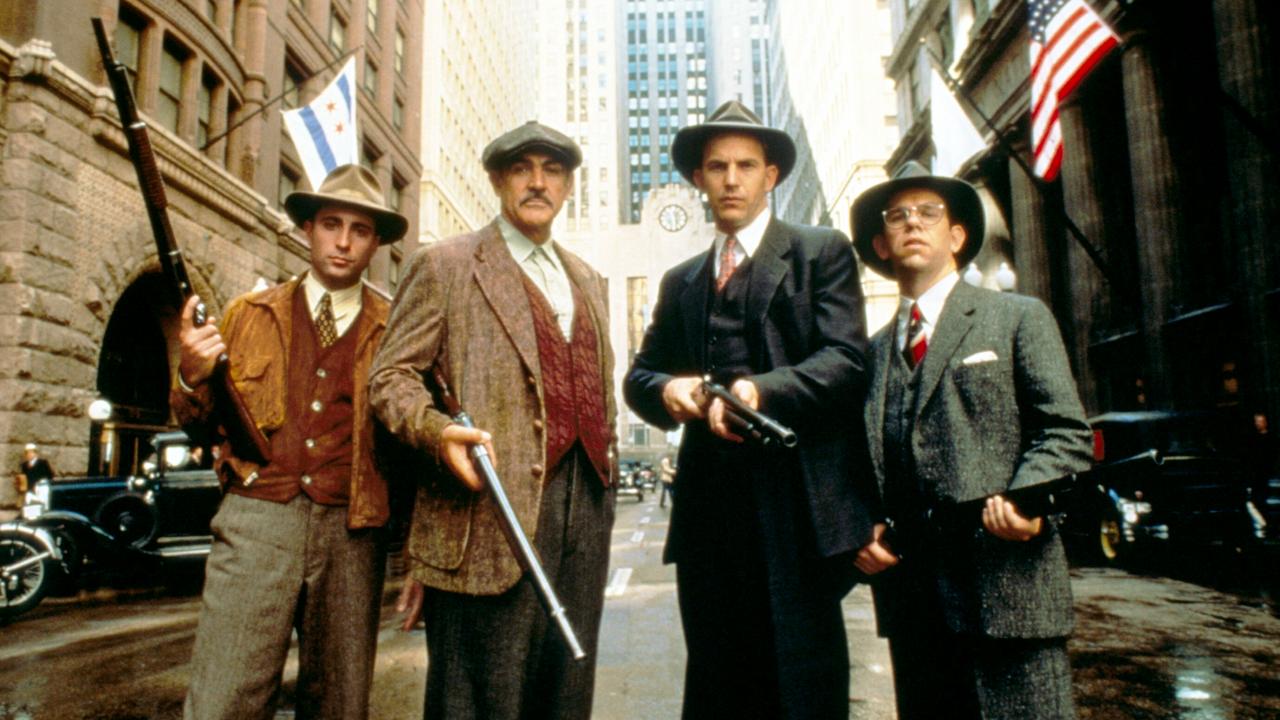 Still aus dem Thriller THE UNTOUCHABLES – DIE UNEBSTECHLICHEN: Vier Männer, gekleidet im Stil der 1930er, stehen bewaffnet in einer Straße in Chicago. 