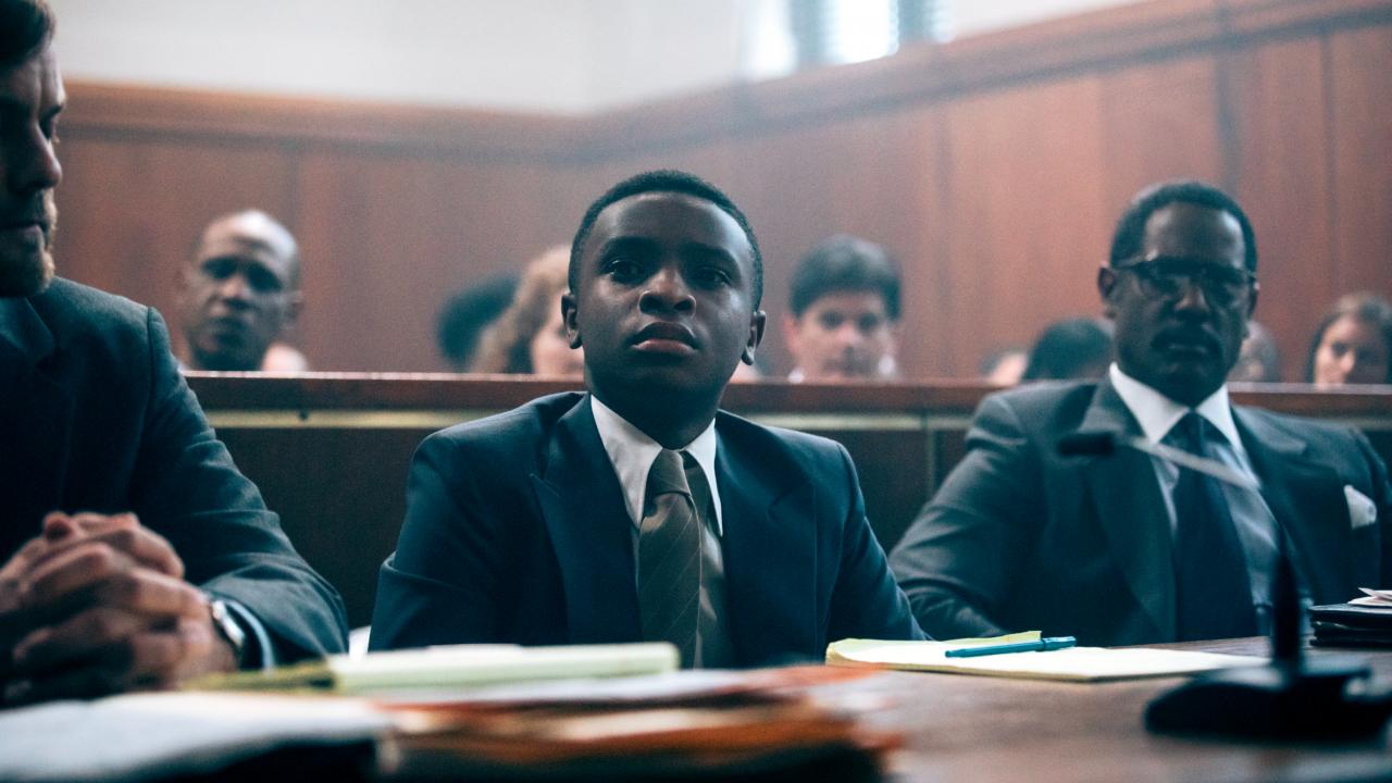 Still aus der Serie WHEN THEY SEE US: Ein junger Schwarzer sitzt im gericht neben zwei Männern. 