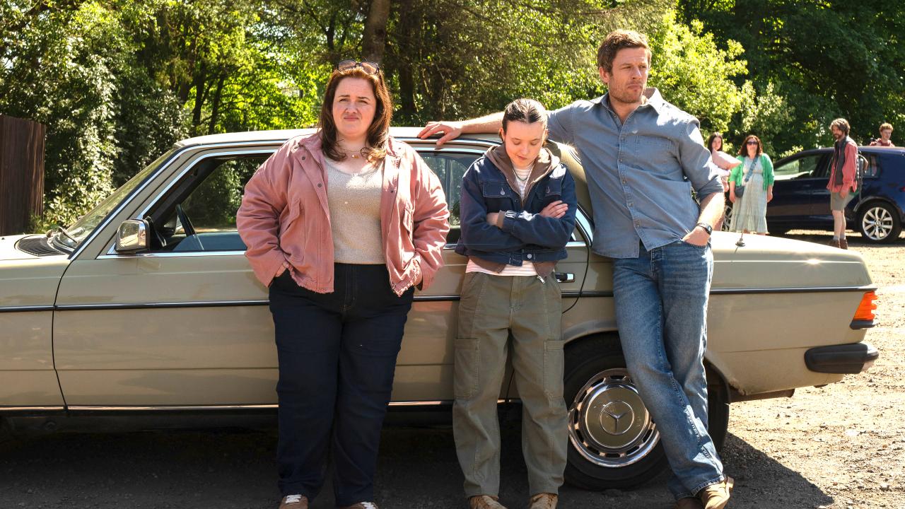 Still aus dem Drama SUNNY DANCER: Ein Teenagerin steht mit ihren Eltern an einem Auto. Das Mädchen schaut zu Boden.