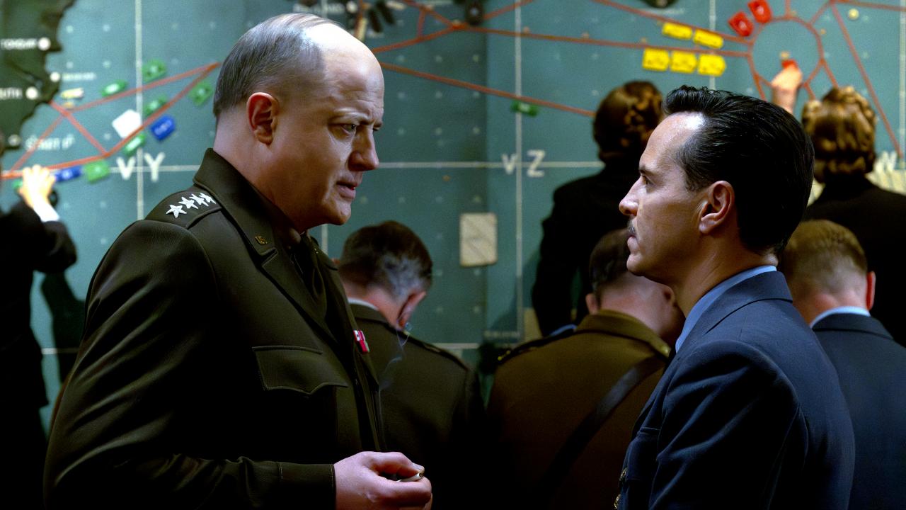 Still aus dem historischen Drama PRESSURE: Zwei Männer stehen sich im Gespräch gegenüber.. Im Hintergrund ist eine Landkarte zu sehen. Die beiden Männer sollen General Dwight D. Eisenhower und der britische Meteorologe James Stagg sein.