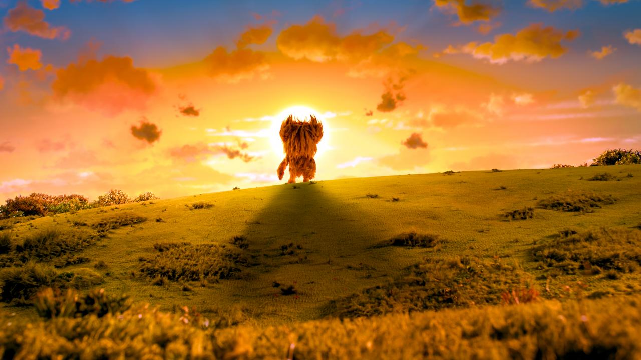 Still aus dem Animationsfilm SHAUN DAS SCHAF – SPUK IM KÜRBISFELD: In einer weiten Landschaft ist vor der umtergehenden Sonne ein zotteliges. großes Wesen zu sehen.