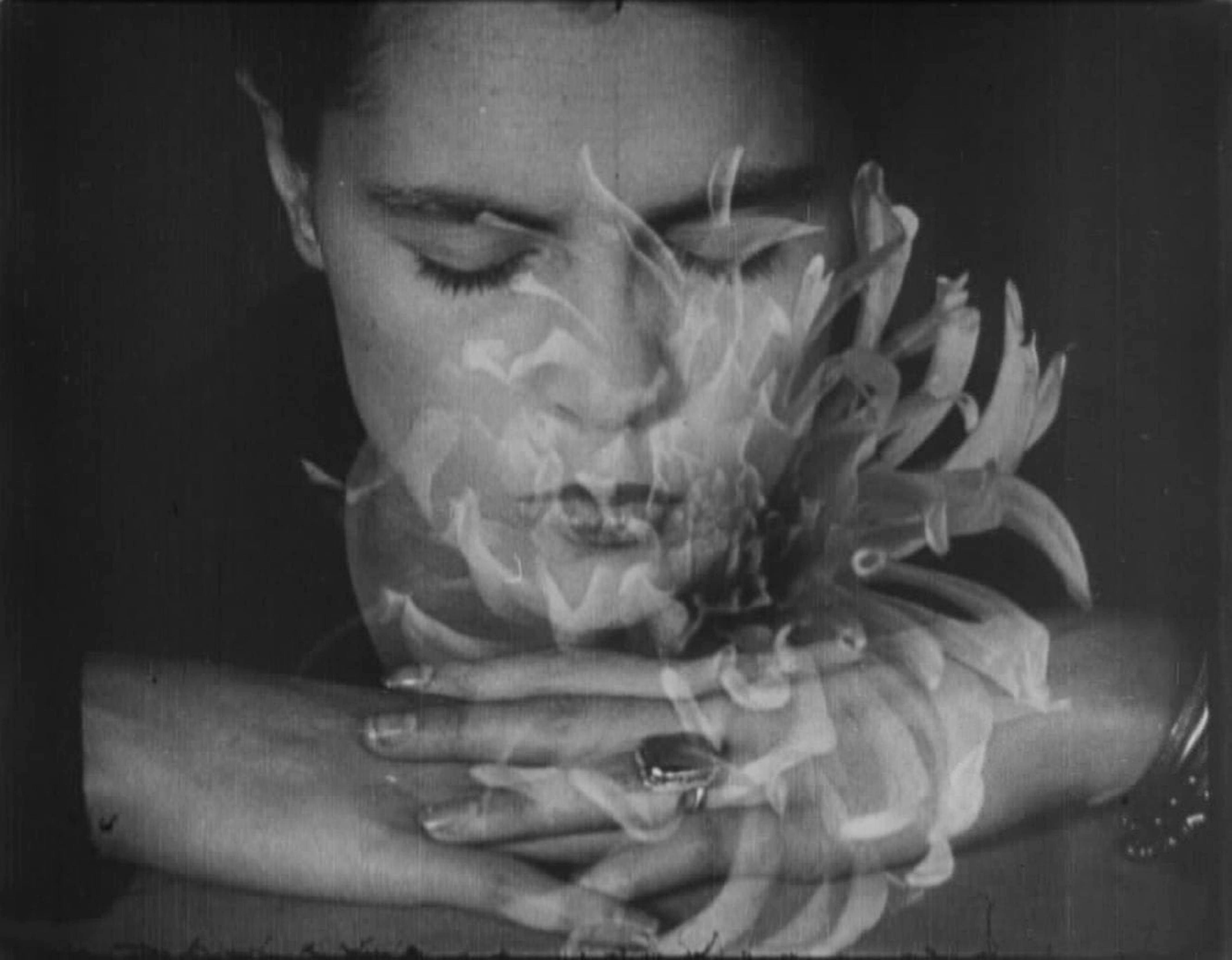 Filmstill aus EMAK-BAKIA: Porträt einer Frau mit geschlossenen Augen, eine Blüte ist als Überblendung zu erkennen 